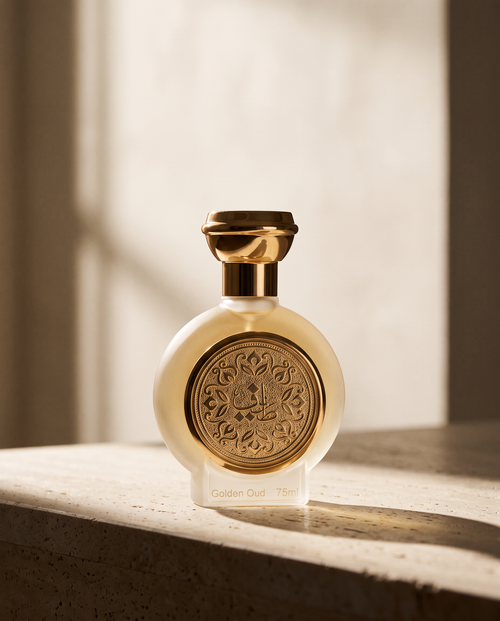 GOLDEN OUD bottle on a travertine ledge in warm directional light